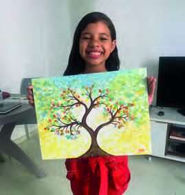 Aluna do curso infantil mostra pintura de árvore colorida