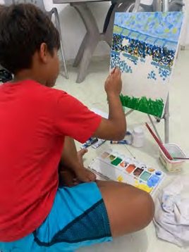 Aluno pintando paisagem em cavalete com aquarela